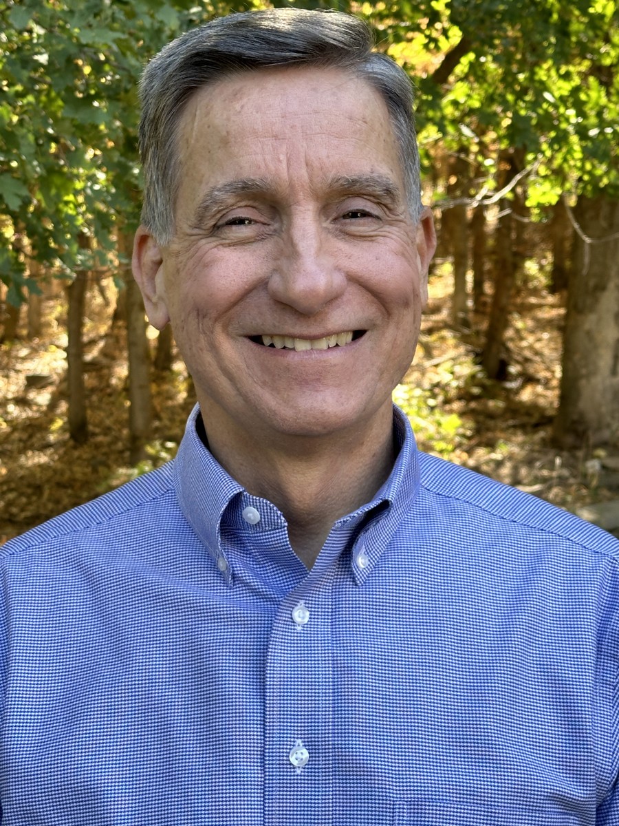 Michael Meyers smiling outdoors in a blue shirt